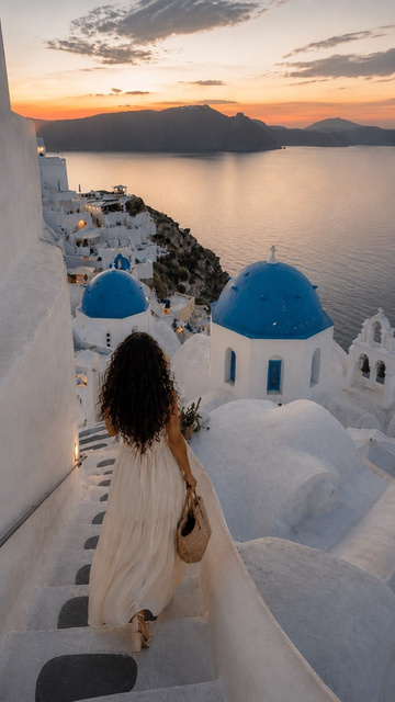 Destination Diva walking down whitewashed steps in Santorini at sunset